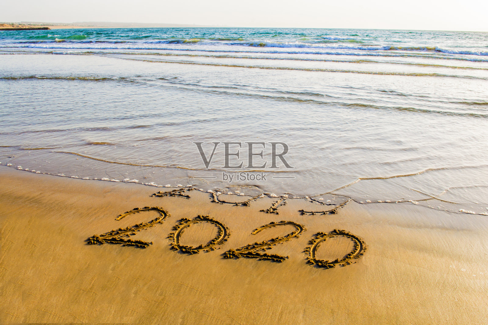 海滩上的“2020年新年快乐”文字。即将到来的2020年和即将离开的2019年的抽象背景照片照片摄影图片