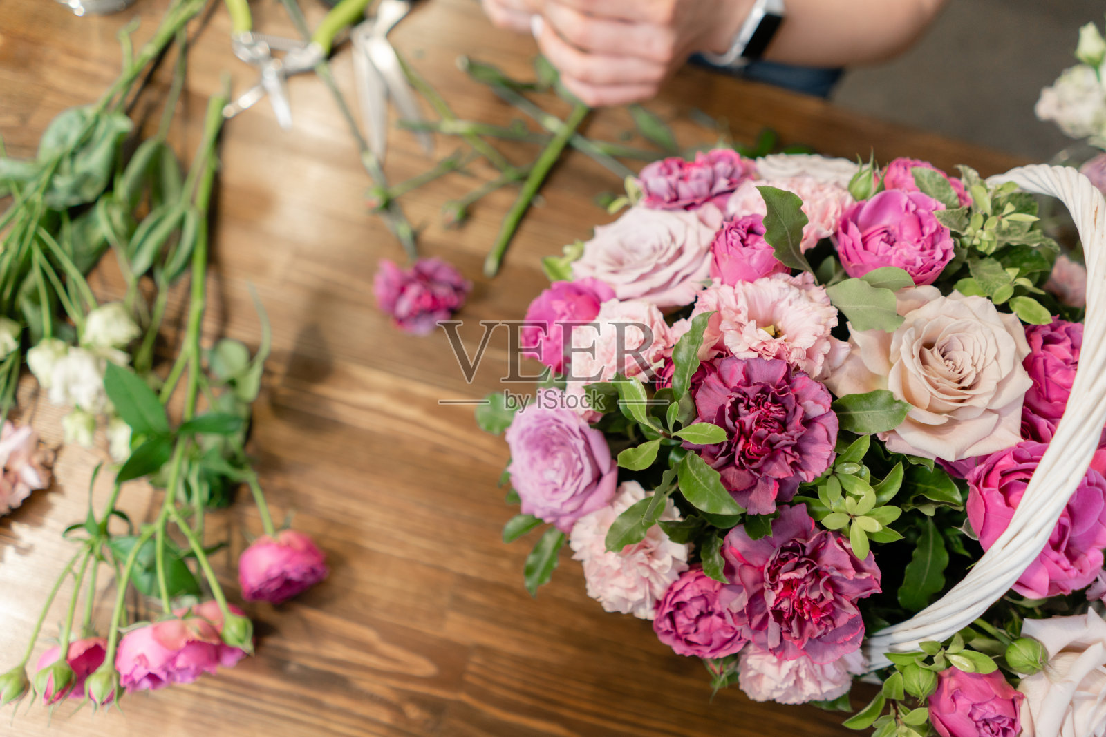 英俊的新鲜的花束。花交付。女花商在柳条篮子里制作插花。一束美丽的混合鲜花。花店概念。照片摄影图片