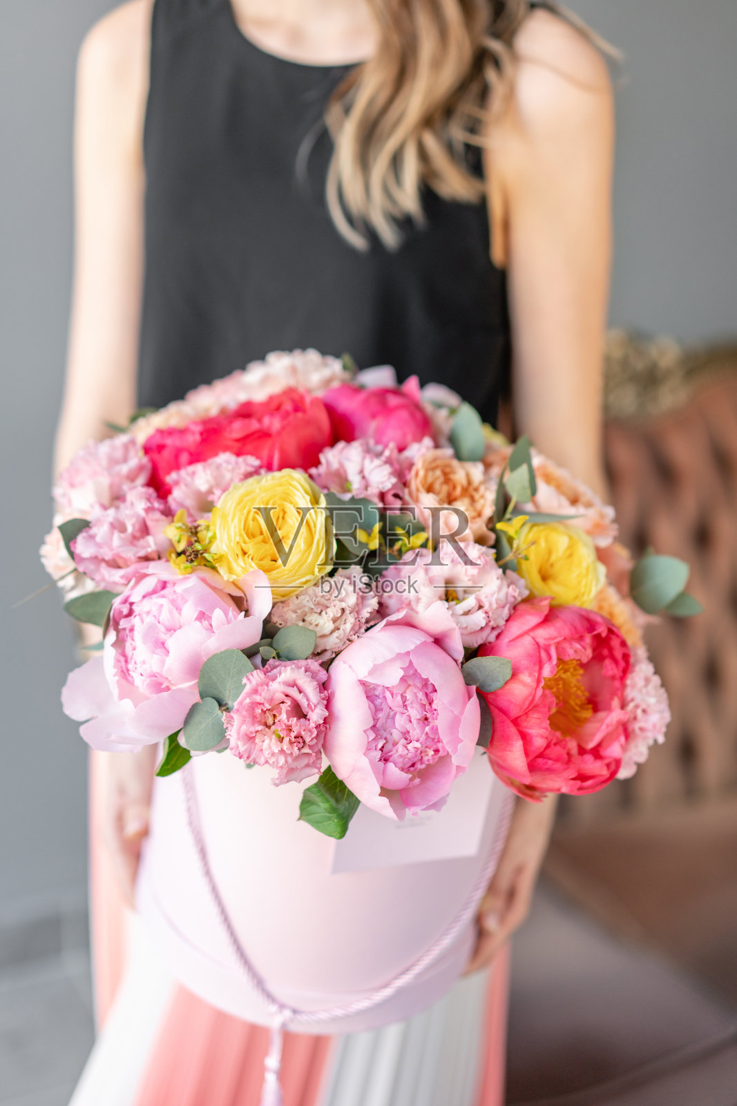 珊瑚和粉红牡丹。女人手里捧着美丽的花束。装在装帽子的圆盒子里。花店概念。鲜切花交付照片摄影图片