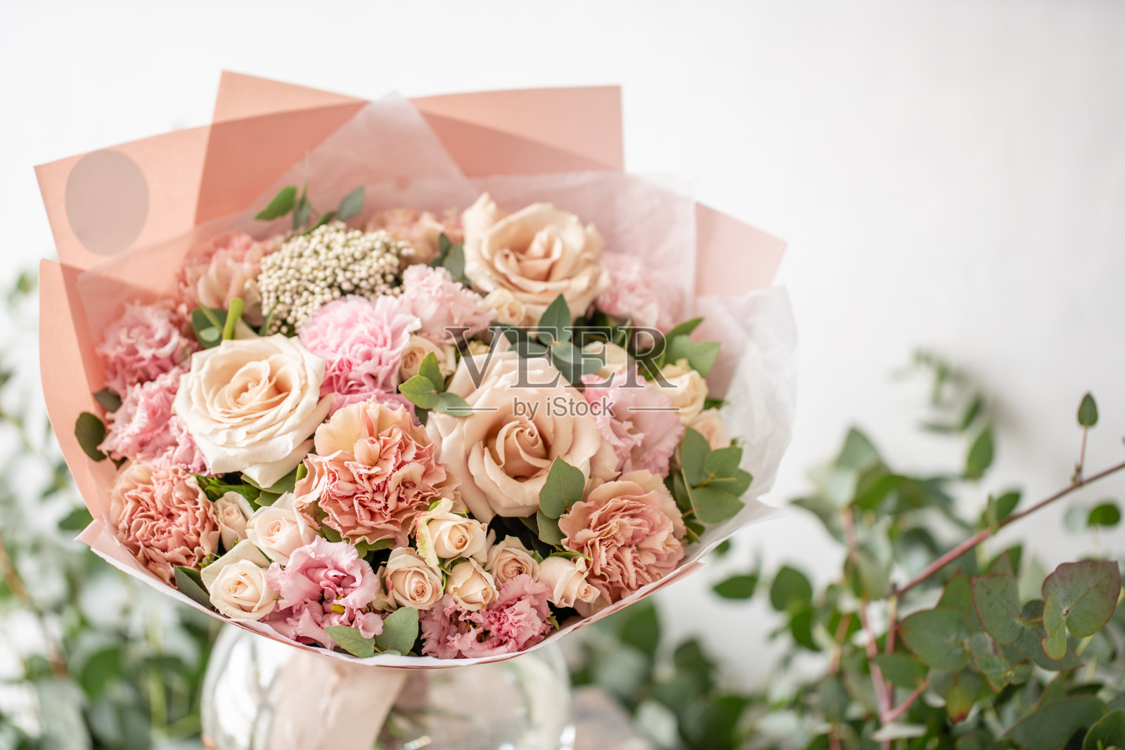 木桌上的花瓶里插着一束漂亮的鲜花。花店花匠的工作。柔和的色调颜色照片摄影图片