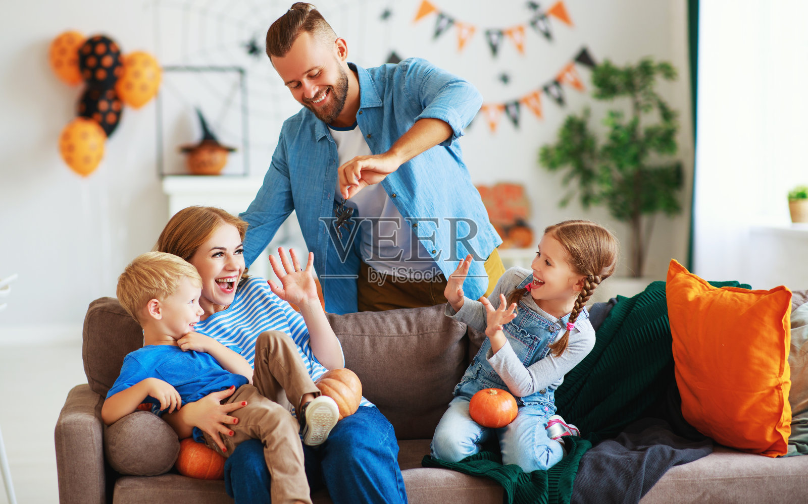 快乐的家庭妈妈爸爸和孩子们准备万圣节用南瓜装饰家和欢笑，玩和蜘蛛惊吓照片摄影图片