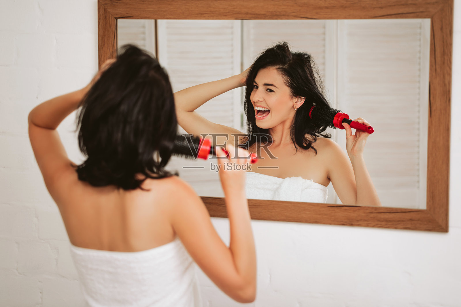 一名年轻女子在镜子前梳着健康的头发照片摄影图片