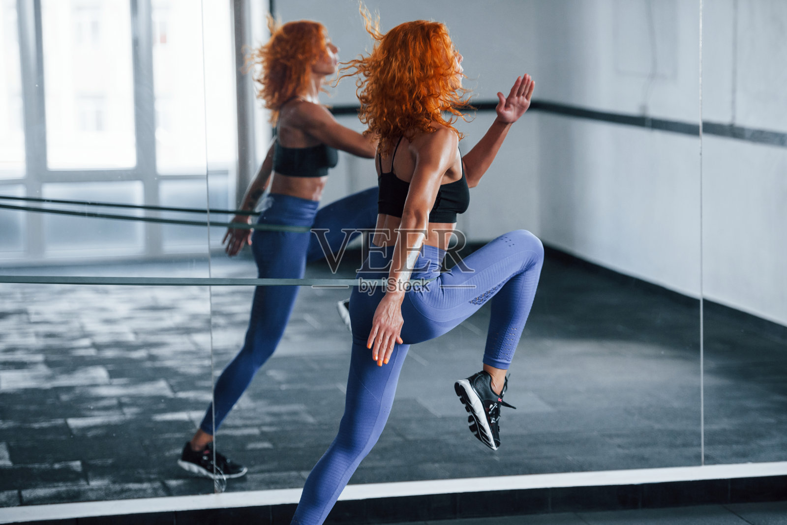 跑到镜子旁边。喜欢运动的红发女孩白天去健身房健身。肌肉发达的身体类型照片摄影图片
