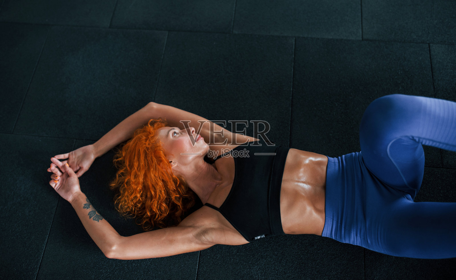 躺着。喜欢运动的红发女孩白天去健身房健身。肌肉发达的身体类型照片摄影图片