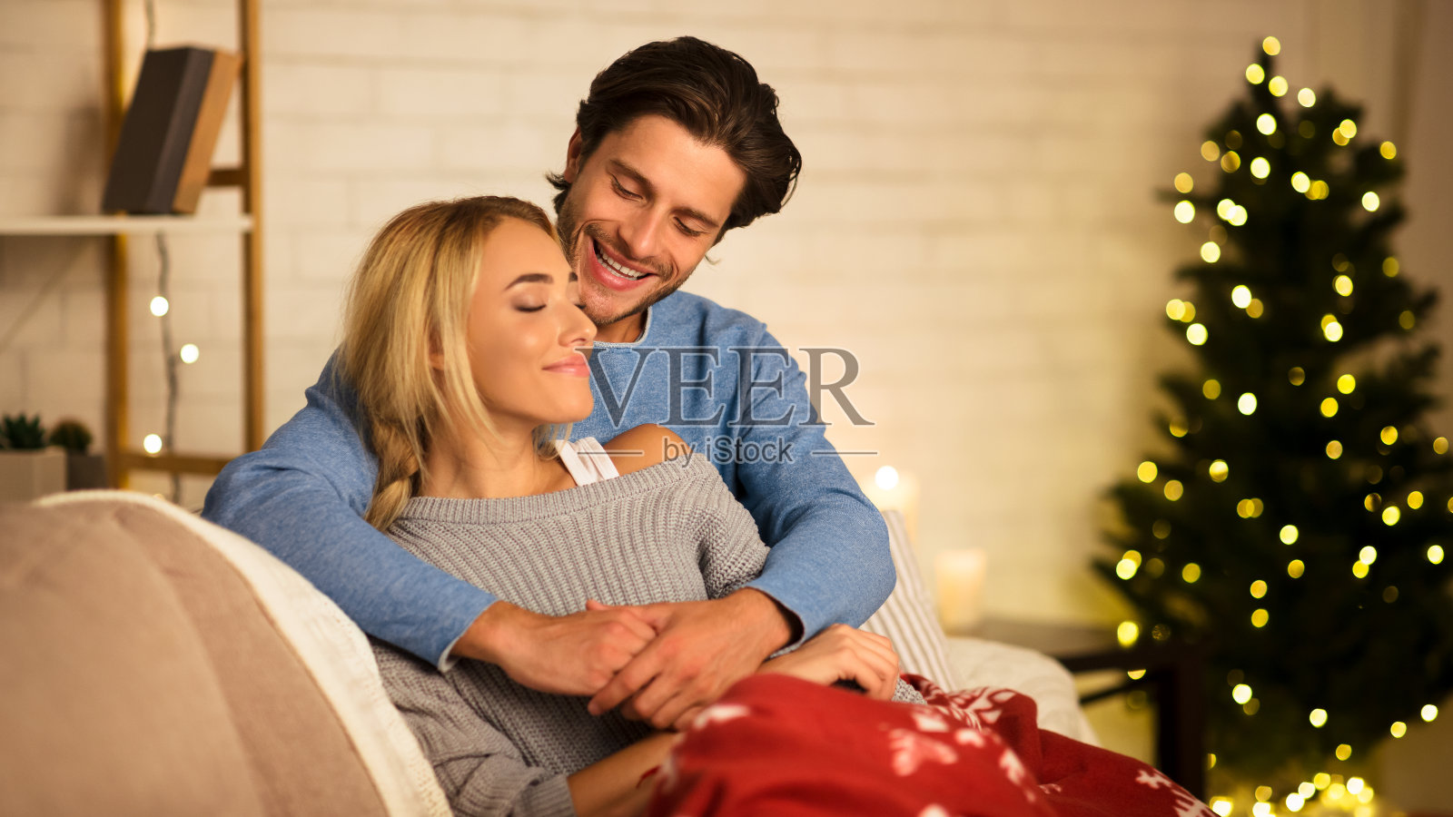 舒适的圣诞夜。一对恩爱的情侣在圣诞树旁拥抱照片摄影图片