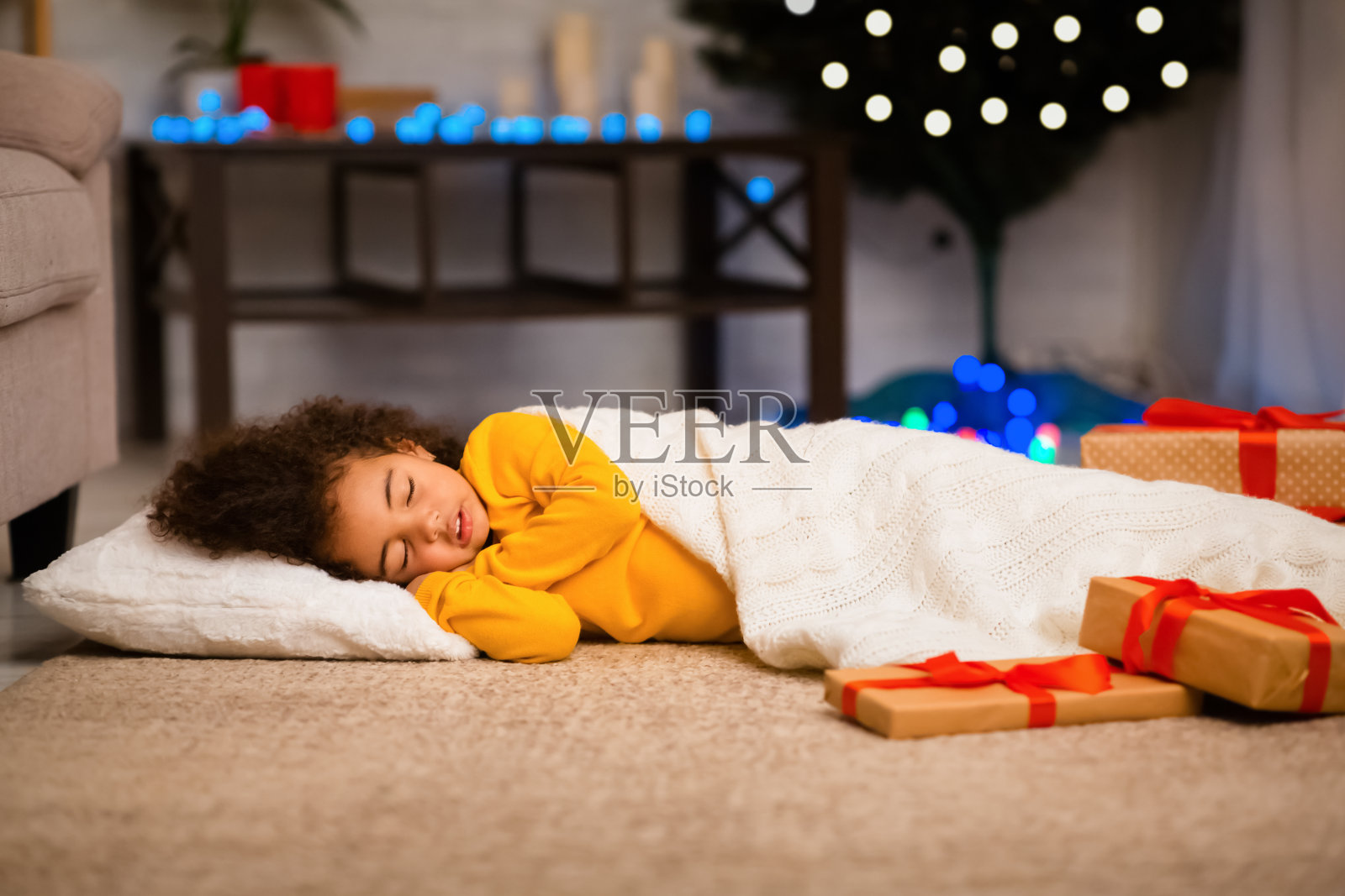 小黑人女孩睡在圣诞树旁的地板上照片摄影图片