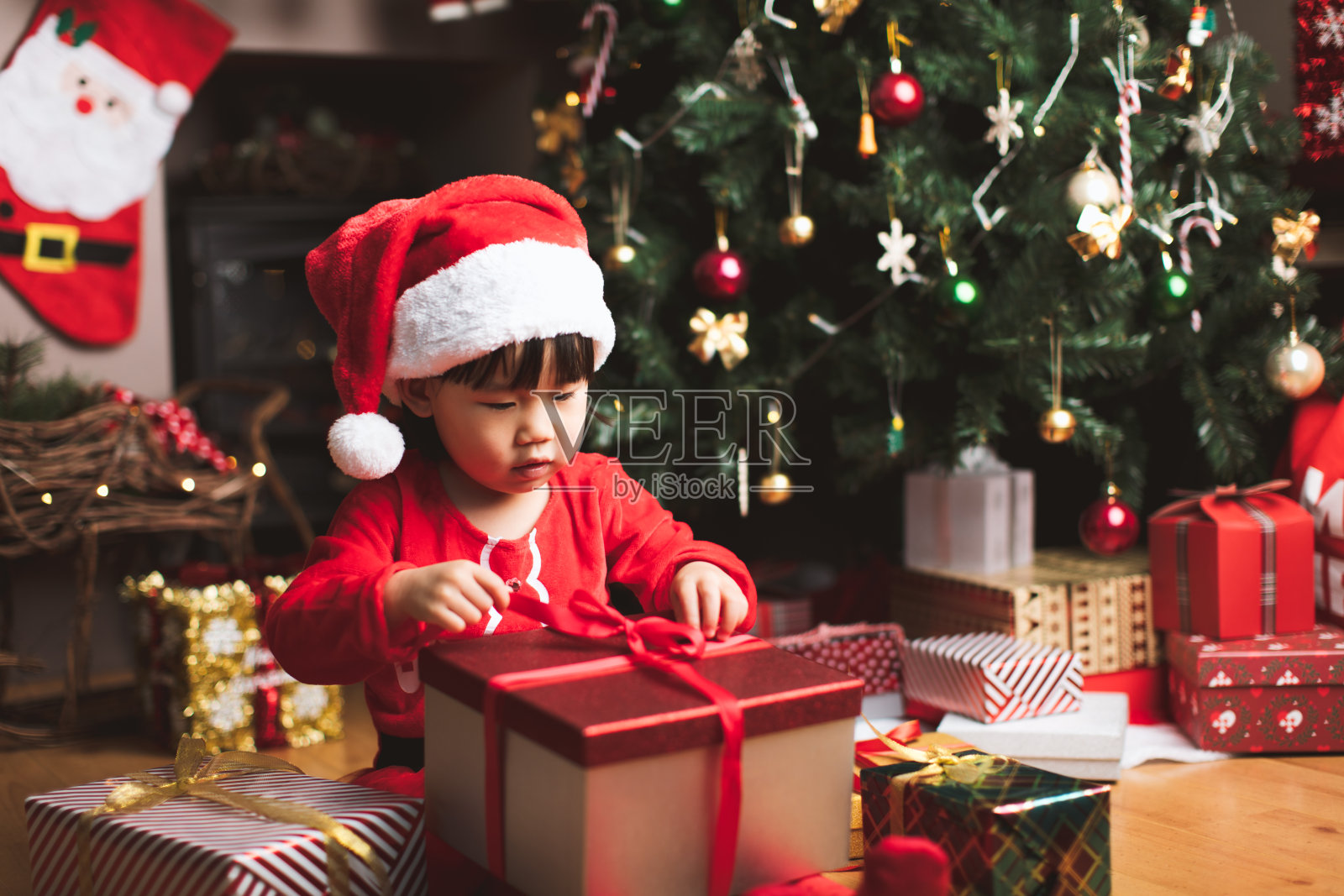 蹒跚学步的小女孩在圣诞树前得到圣诞礼物照片摄影图片