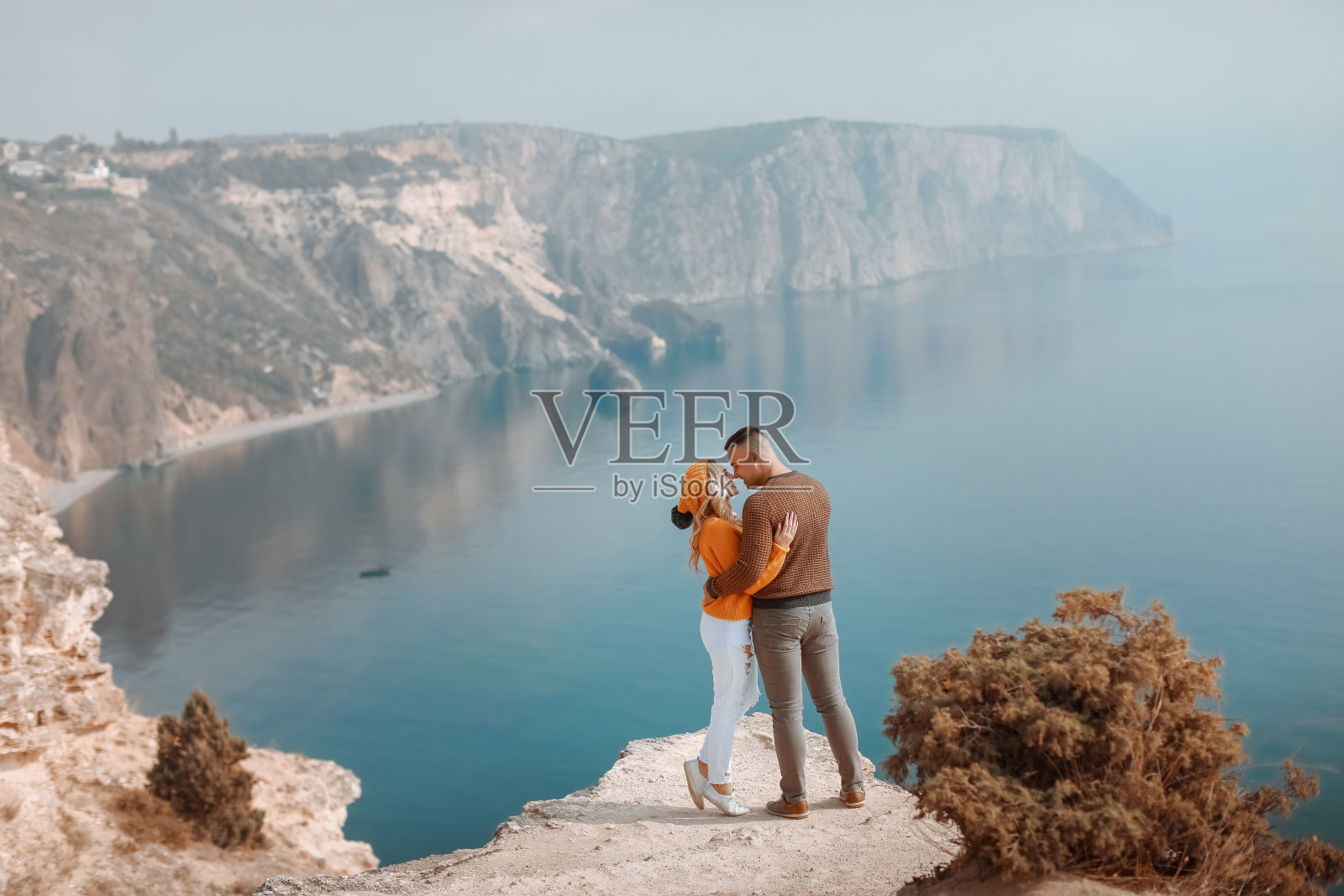 一名年轻男子和一名女子站在山顶上，海湾的全景尽收眼底照片摄影图片
