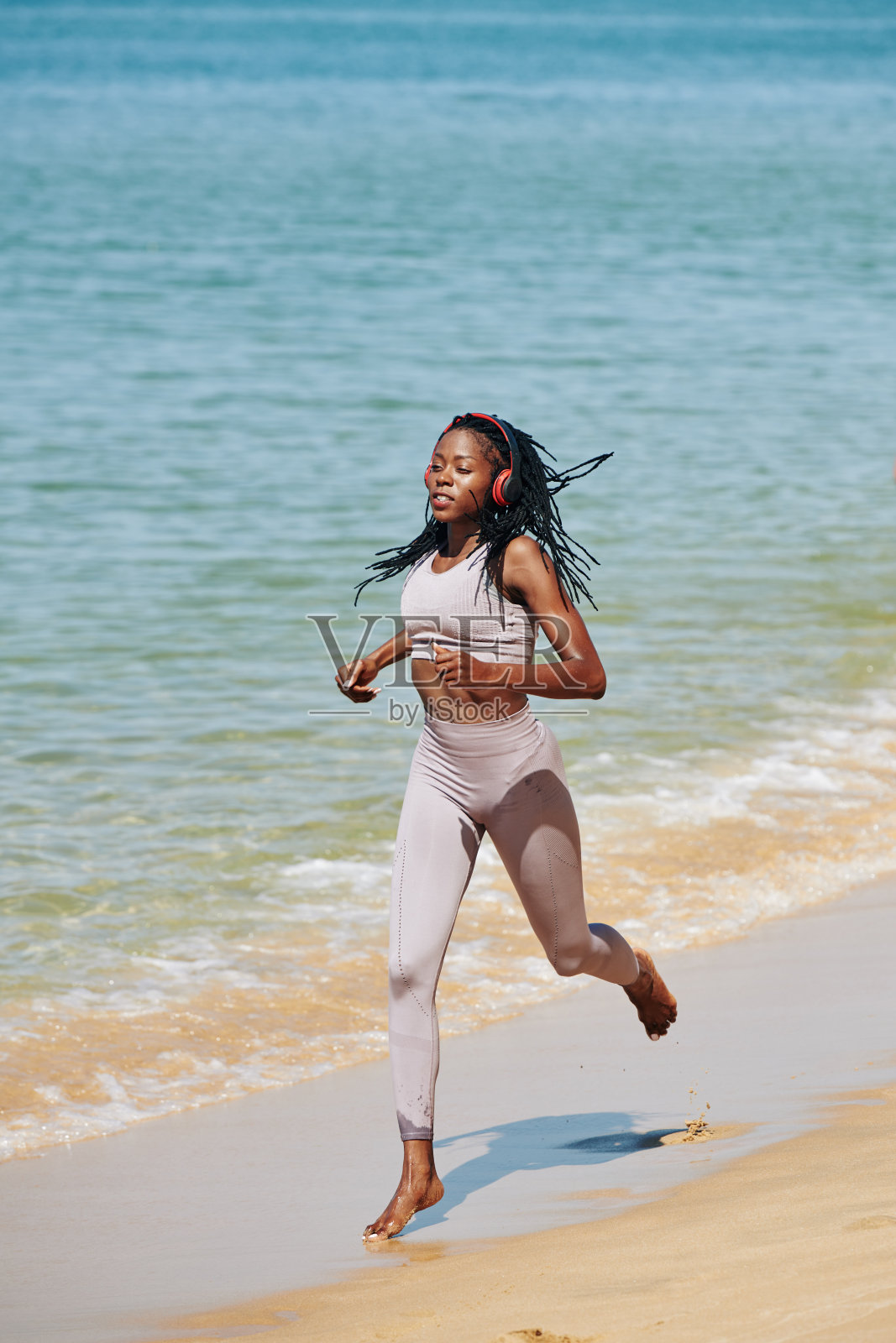 在海滩上跑步的女运动员照片摄影图片