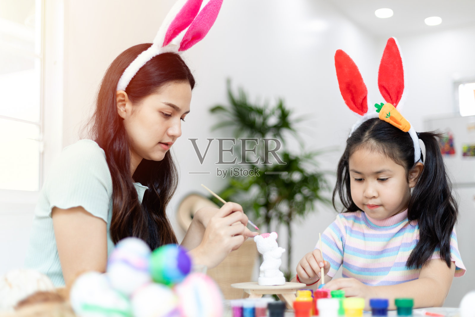 两个亚洲姐妹带着兴趣在混凝土娃娃上画彩色水彩画，一起做活动，在客厅里。照片摄影图片