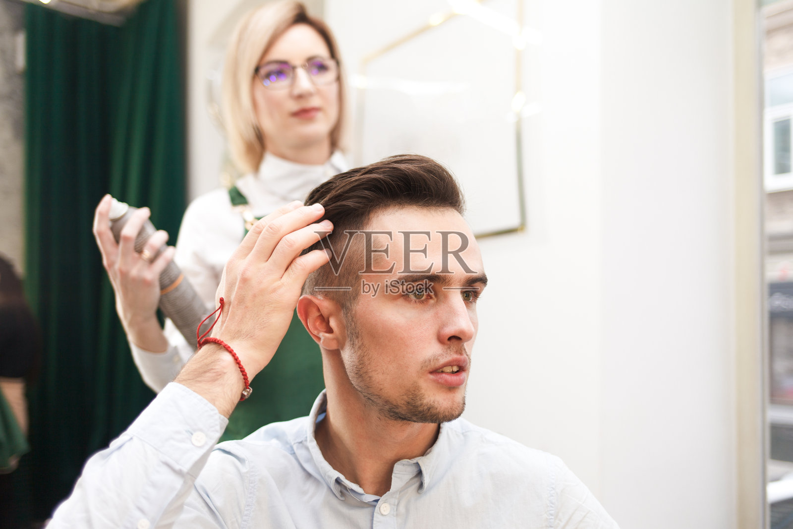 发型师与顾客评估理发后的效果。发型师为男士做发型照片摄影图片