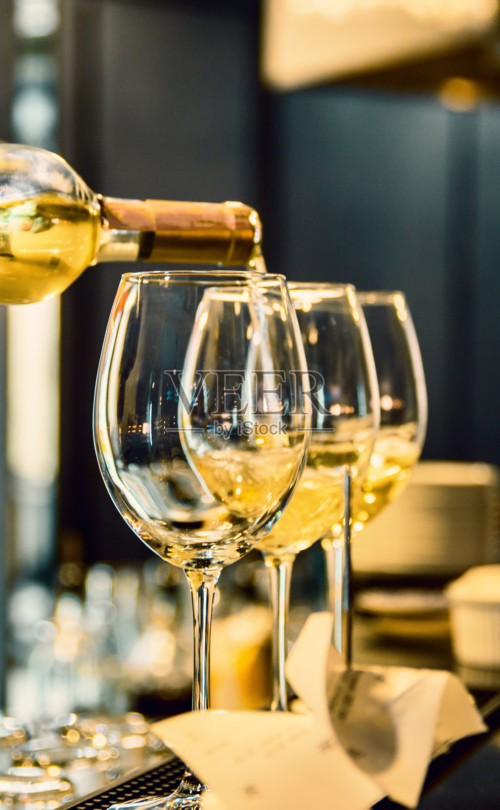 在咖啡馆或酒吧里，调酒师把白葡萄酒倒进杯子里照片摄影图片