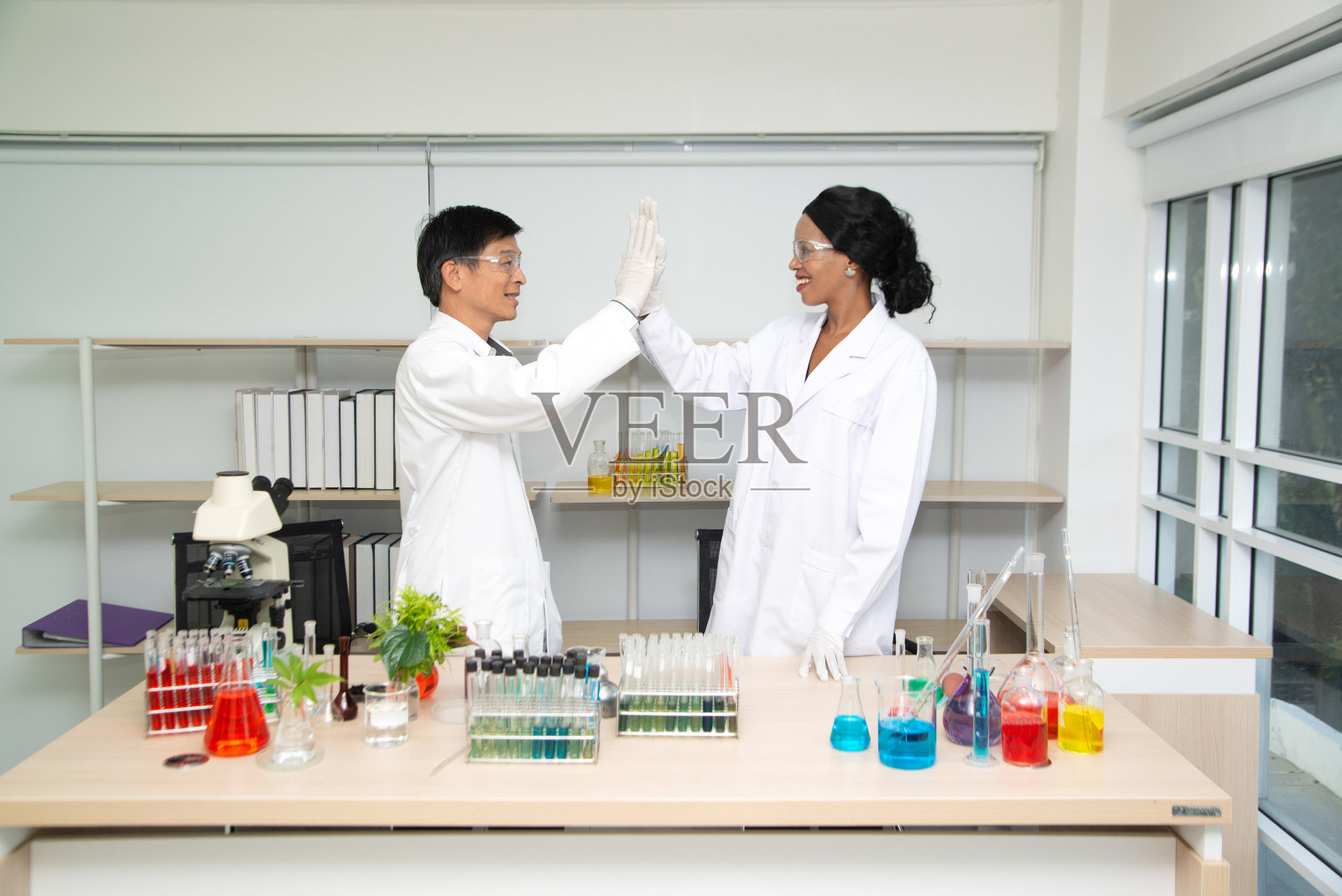 两名科学家站着，摆出姿势，露出高兴的样子。现代实验室页面，代表研究成功的研究。照片摄影图片