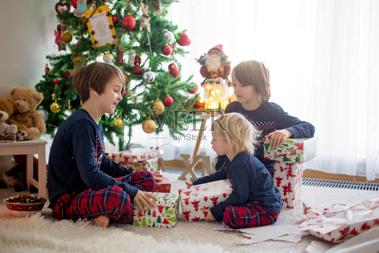 快乐的孩子们，在圣诞节打开礼物照片摄影图片