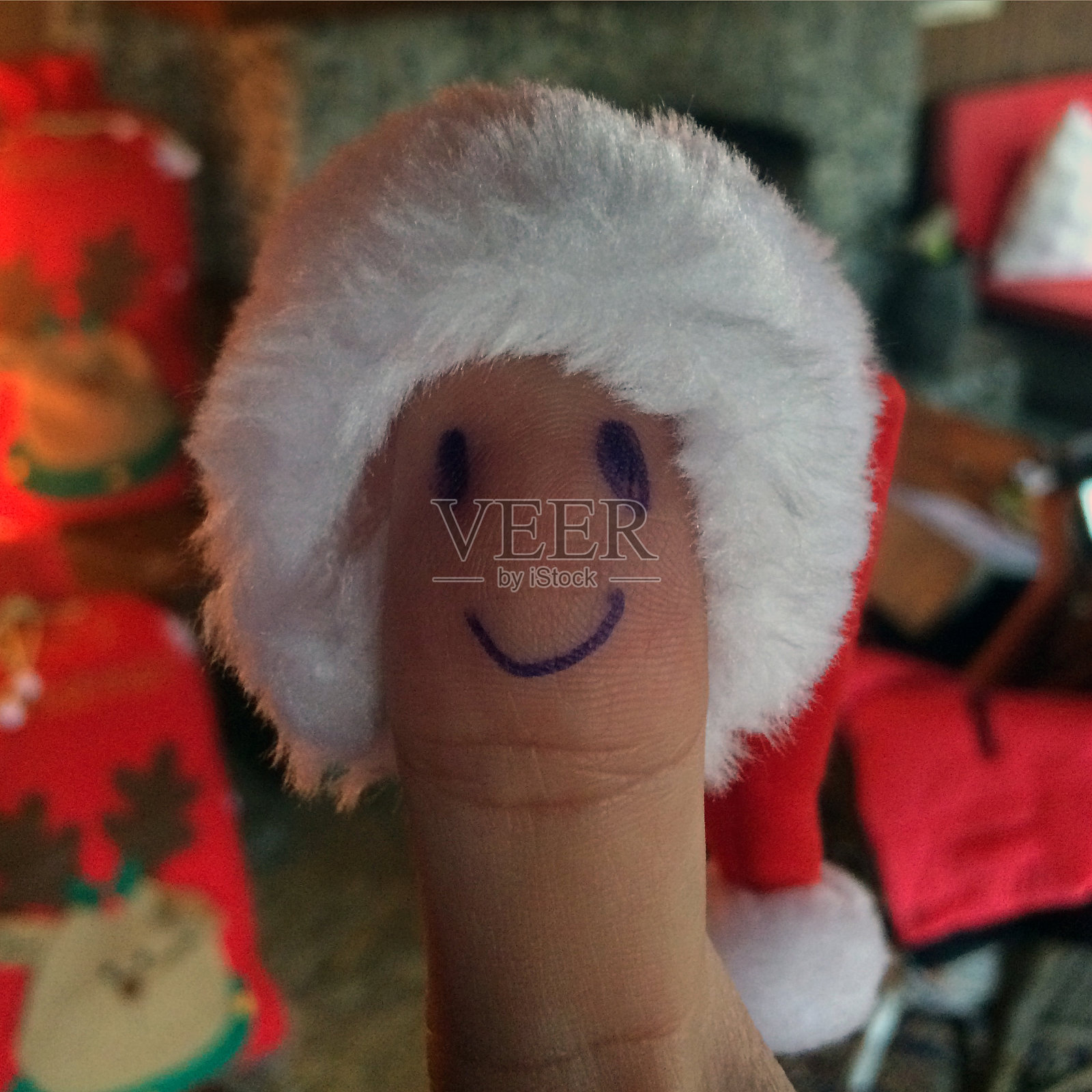 滑稽的脸画的男性拇指手指戴着圣诞老人的帽子。照片摄影图片