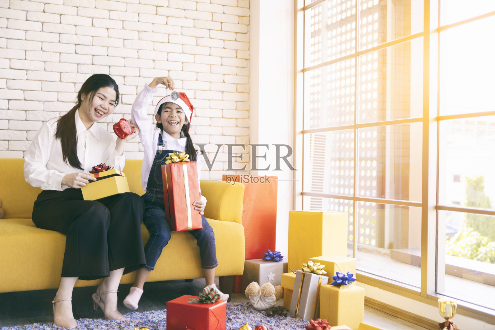 快乐的妈妈和女儿在家里的圣诞树上放礼物。照片摄影图片