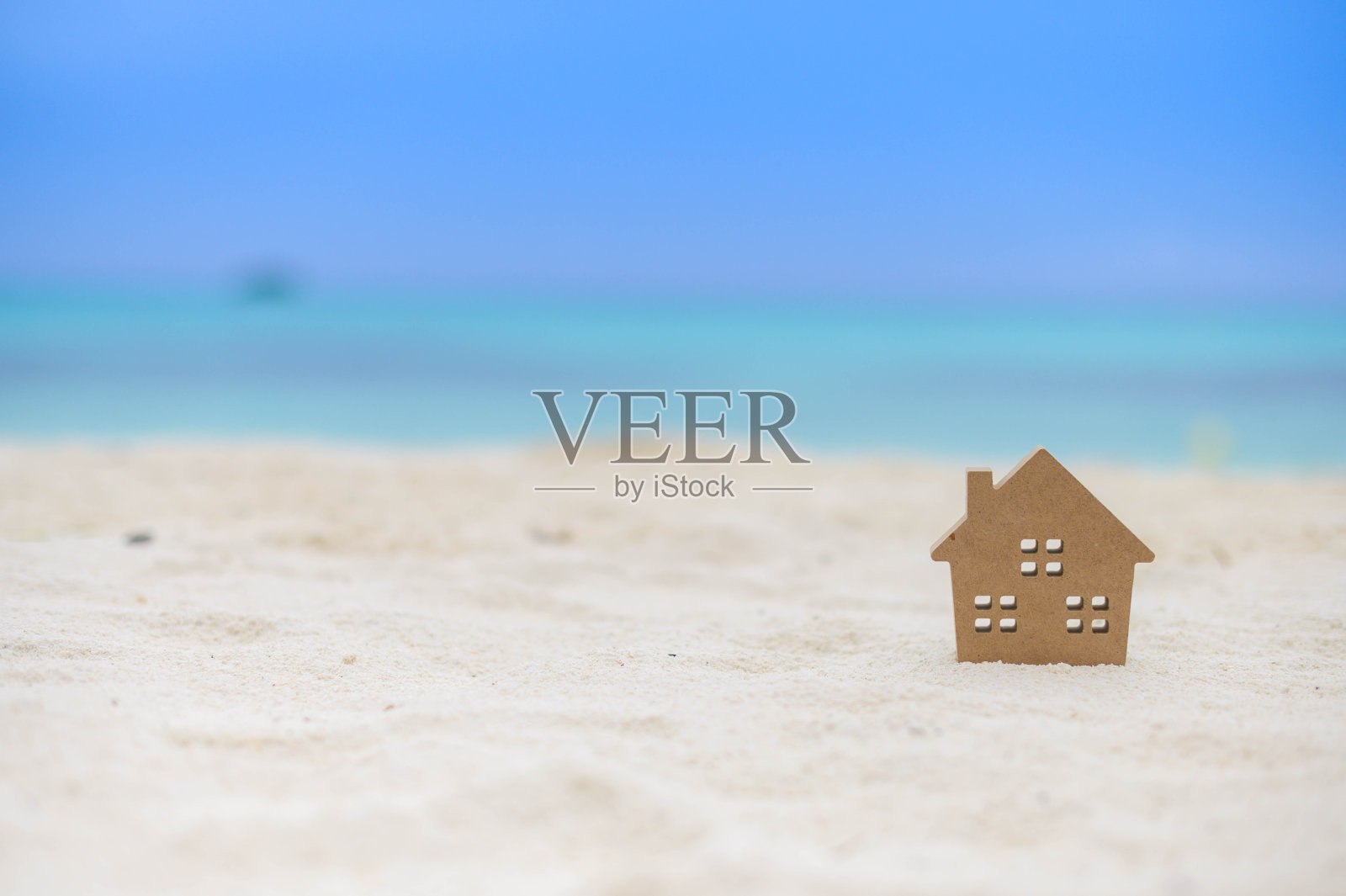 在沙滩上的小房子模型与蓝天的背景。复制家庭生活方式空间和商业地产概念。照片摄影图片