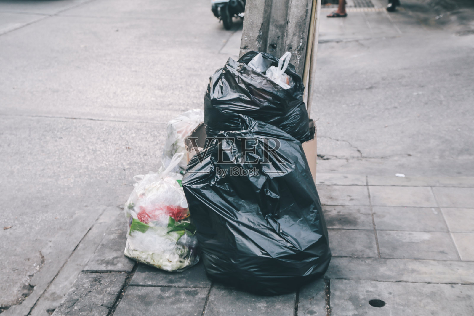 大城市路边的人行道上堆放着黑色垃圾，公园里堆放垃圾的黑色塑料袋照片摄影图片