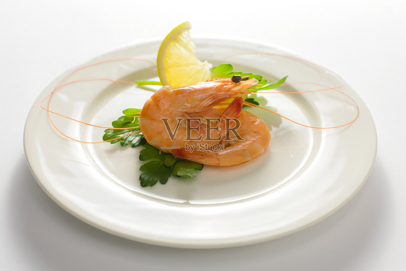 白色的盘子里有美味的虾和柠檬孤立的白色背景。照片摄影图片
