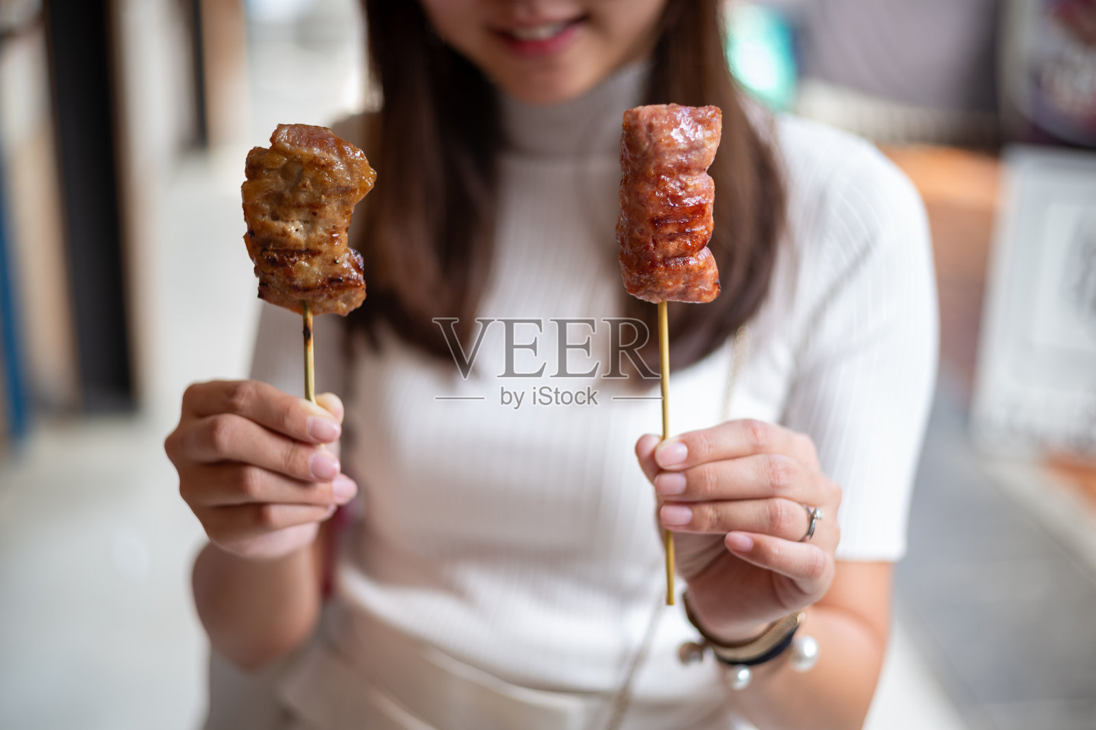 女性亚洲手拿泰国街头食物烤猪肉棒照片摄影图片