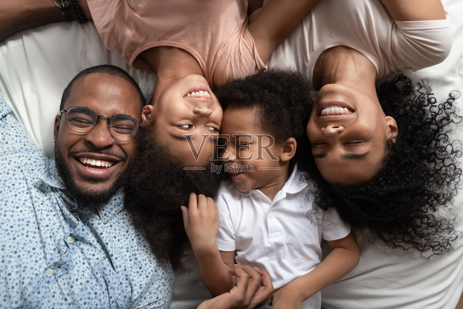 微笑的黑人家庭在床上闭着眼睛休息。照片摄影图片
