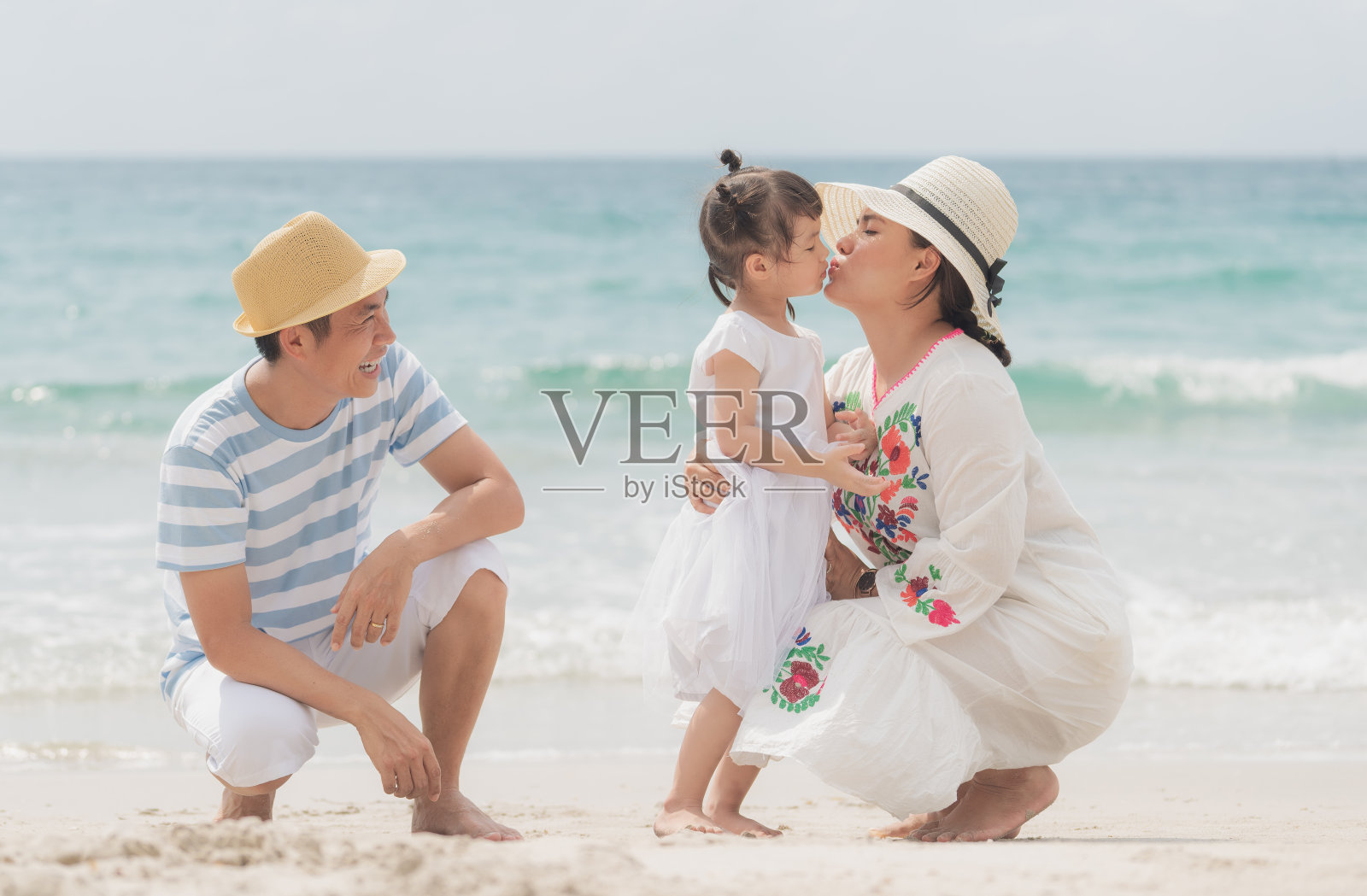 海滩上快乐的亚洲家庭。母亲和女儿互相拥抱，互表爱意，幸福的家庭理念照片摄影图片