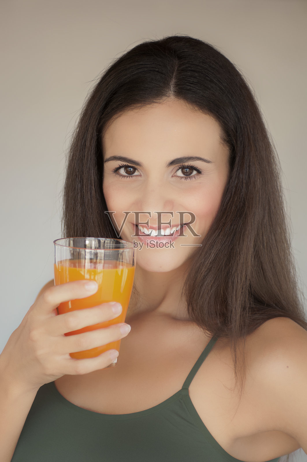 特写的美丽微笑的女人拿着一杯橙汁照片摄影图片