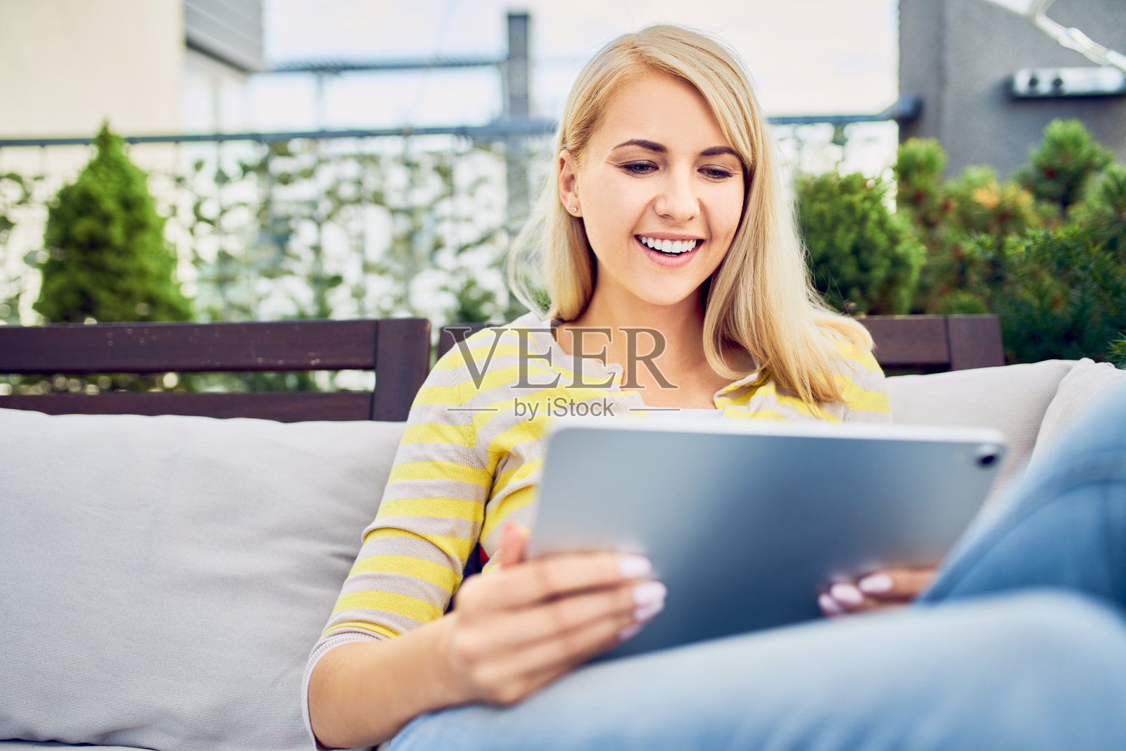 微笑的年轻女子坐在露台休息和使用平板电脑照片摄影图片
