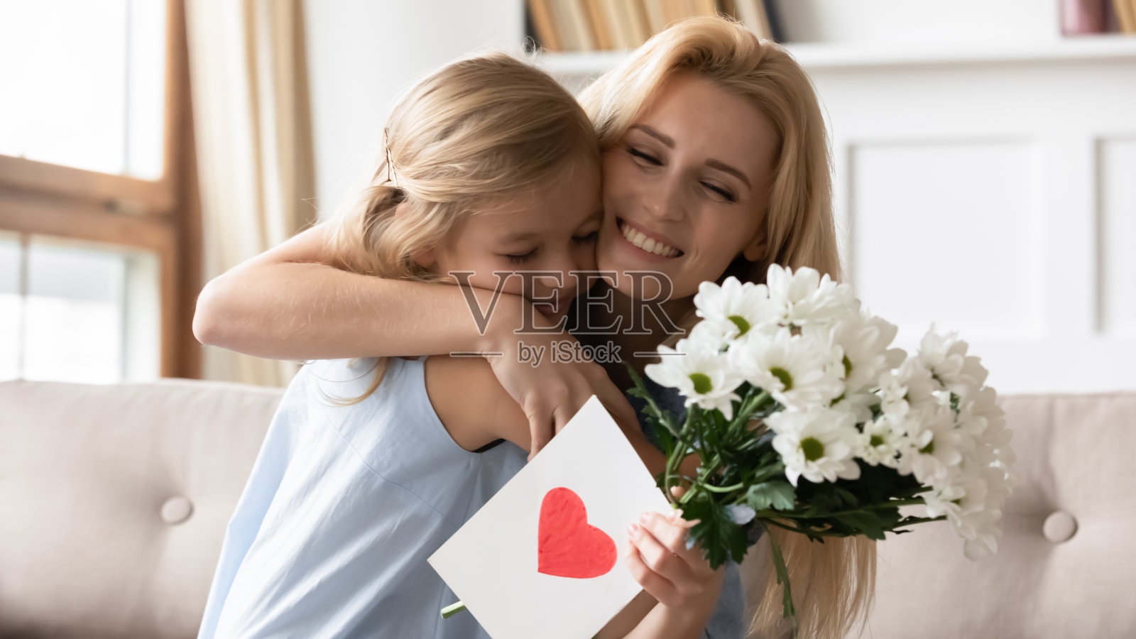 学龄前的小女儿向微笑的妈妈祝贺生日。照片摄影图片