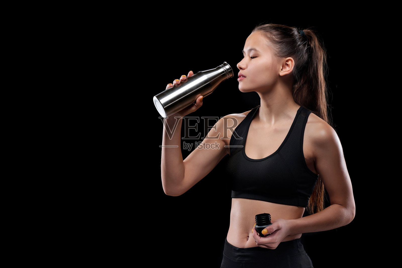 年轻疲惫的女运动员穿着运动服从金属瓶子里喝水照片摄影图片