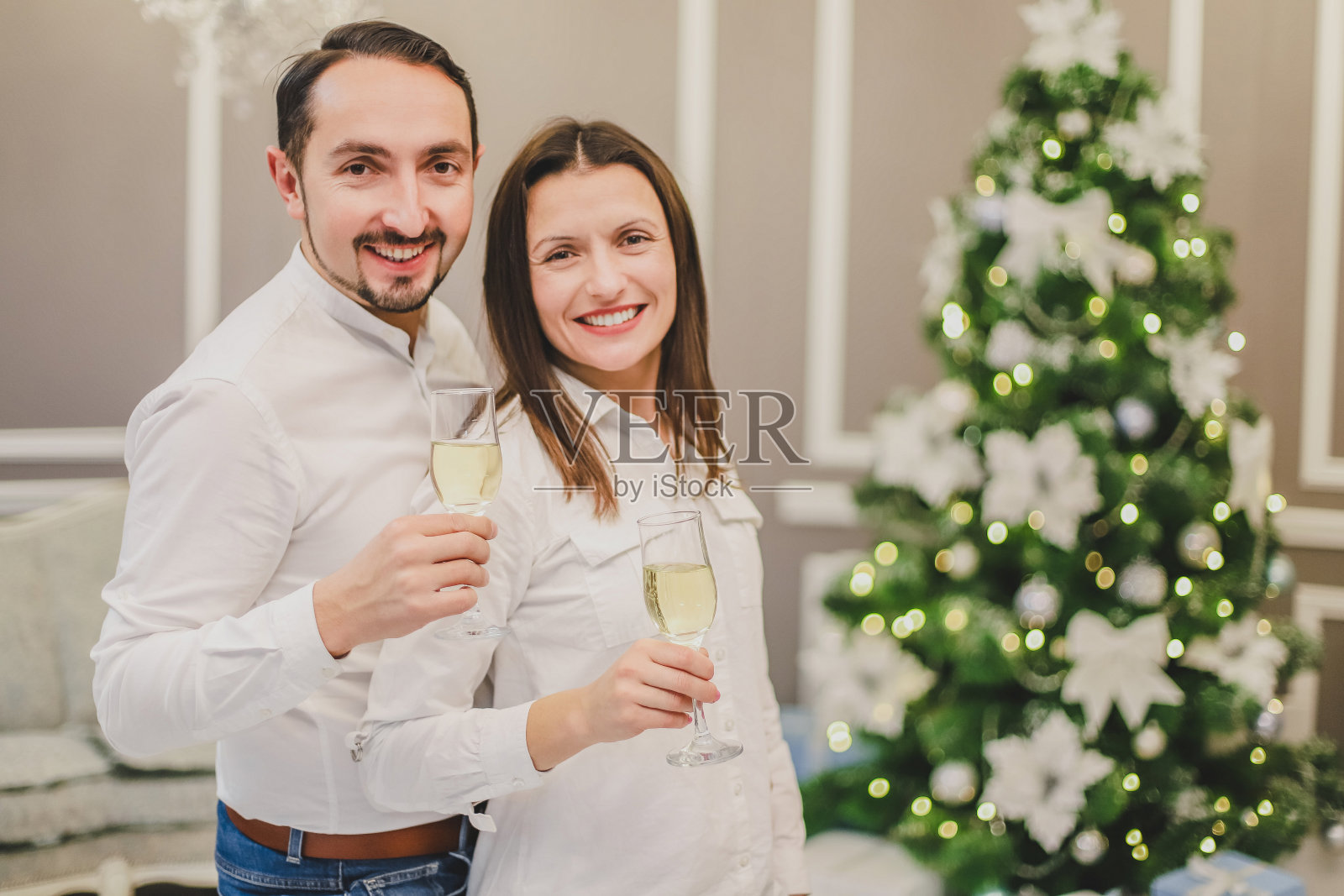 聚会和娱乐的概念。甜蜜的照片，精力充沛的夫妇庆祝，与香槟酒在可爱的新年装饰房间。照片摄影图片