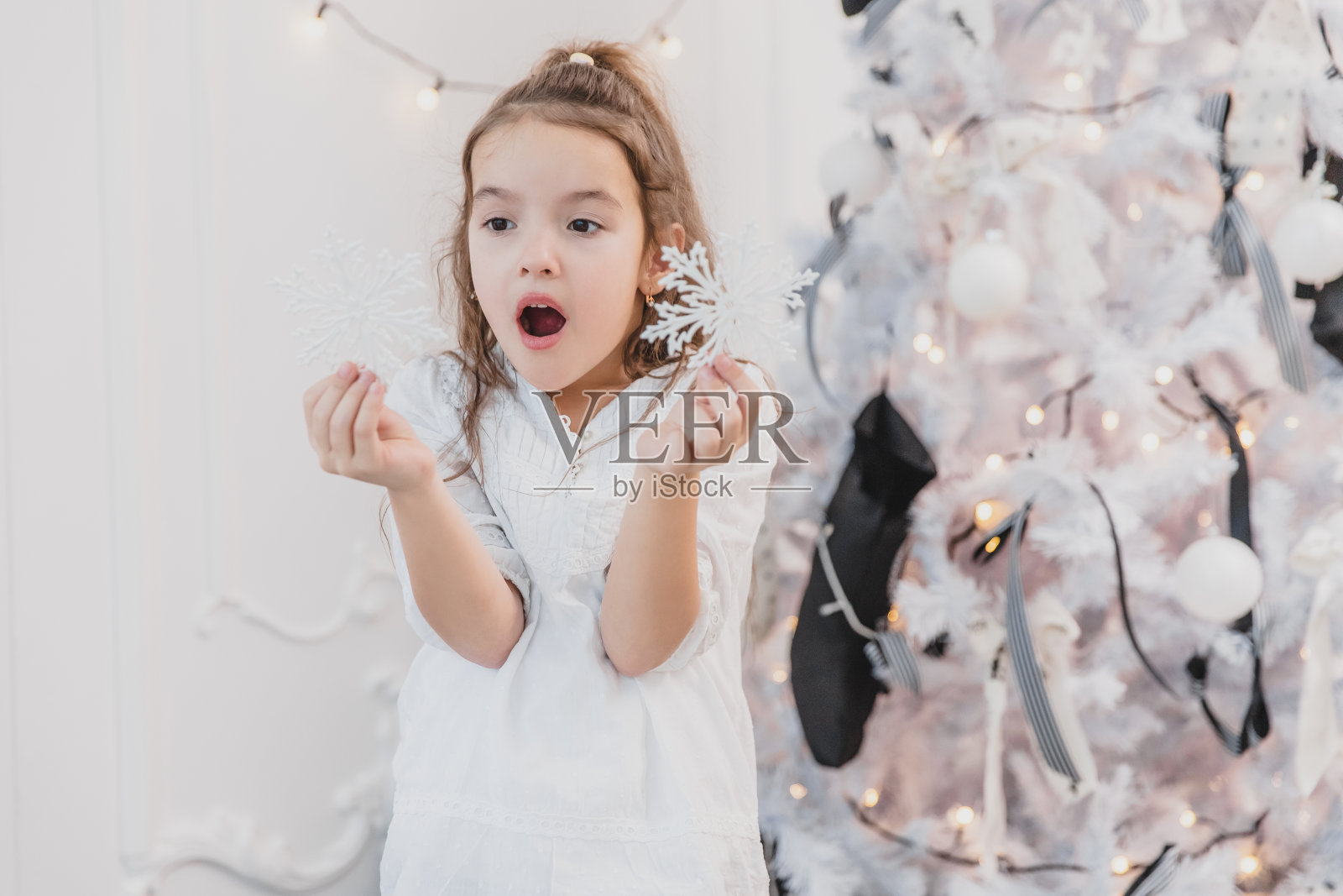 小女孩在装饰冷杉时玩着圣诞树上的雪花。照片摄影图片
