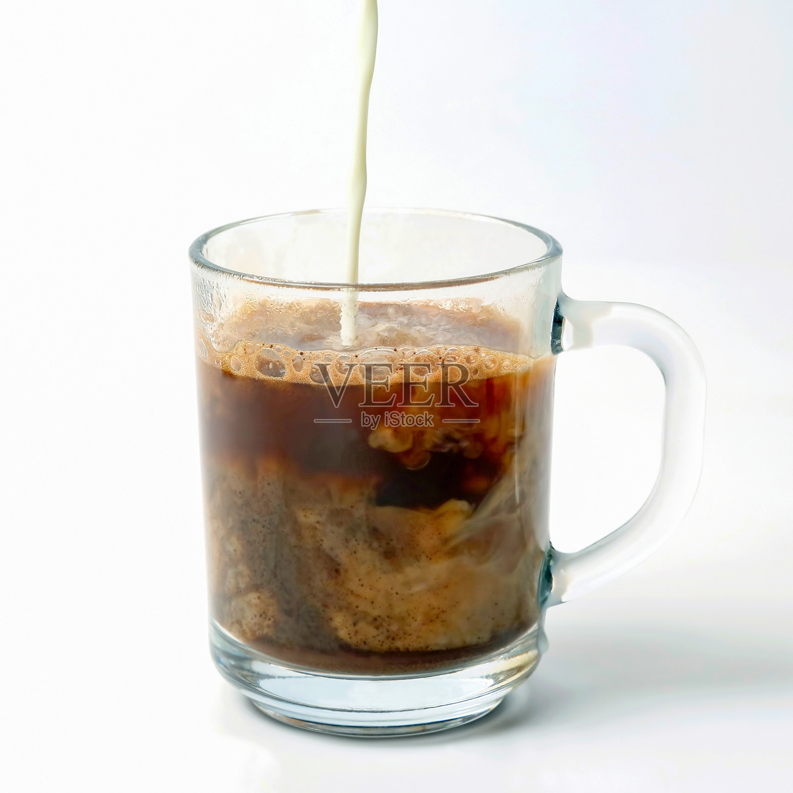 牛奶倒进一杯透明的黑咖啡里照片摄影图片