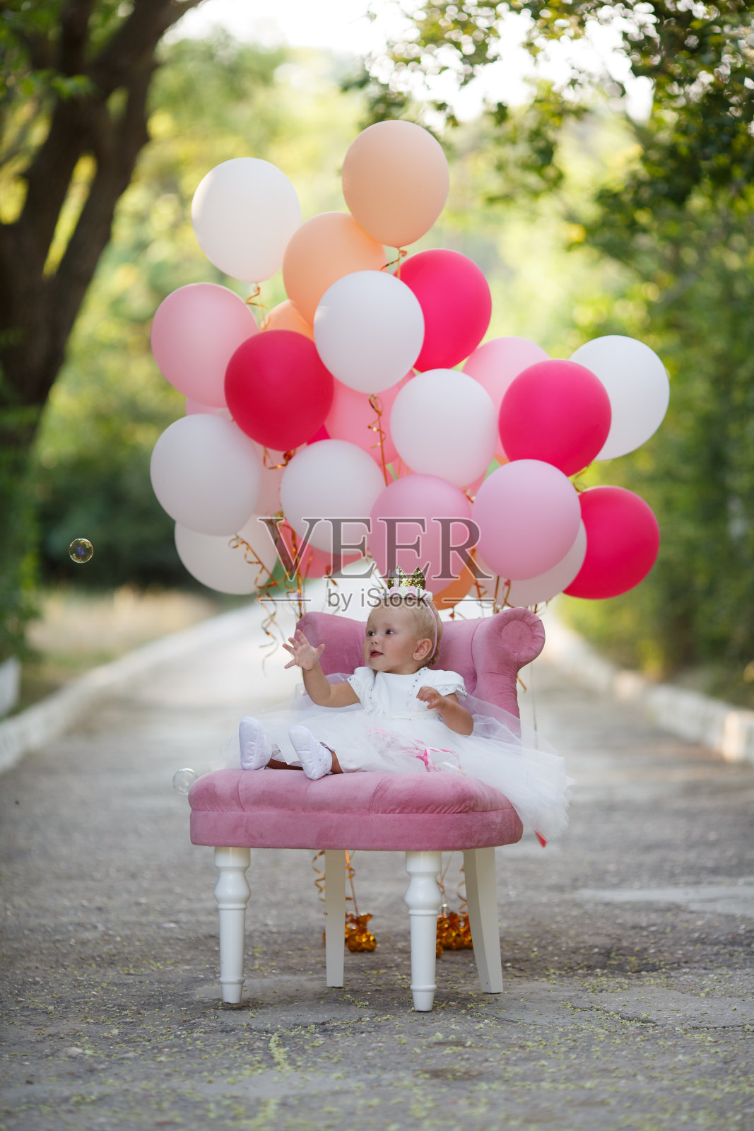 女孩带着粉色的球坐在草地上。生日- 1岁照片摄影图片