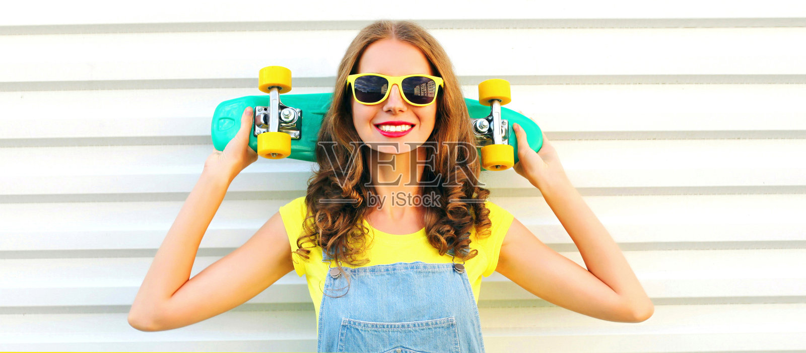 肖像微笑的年轻女子与滑板在白色的背景照片摄影图片