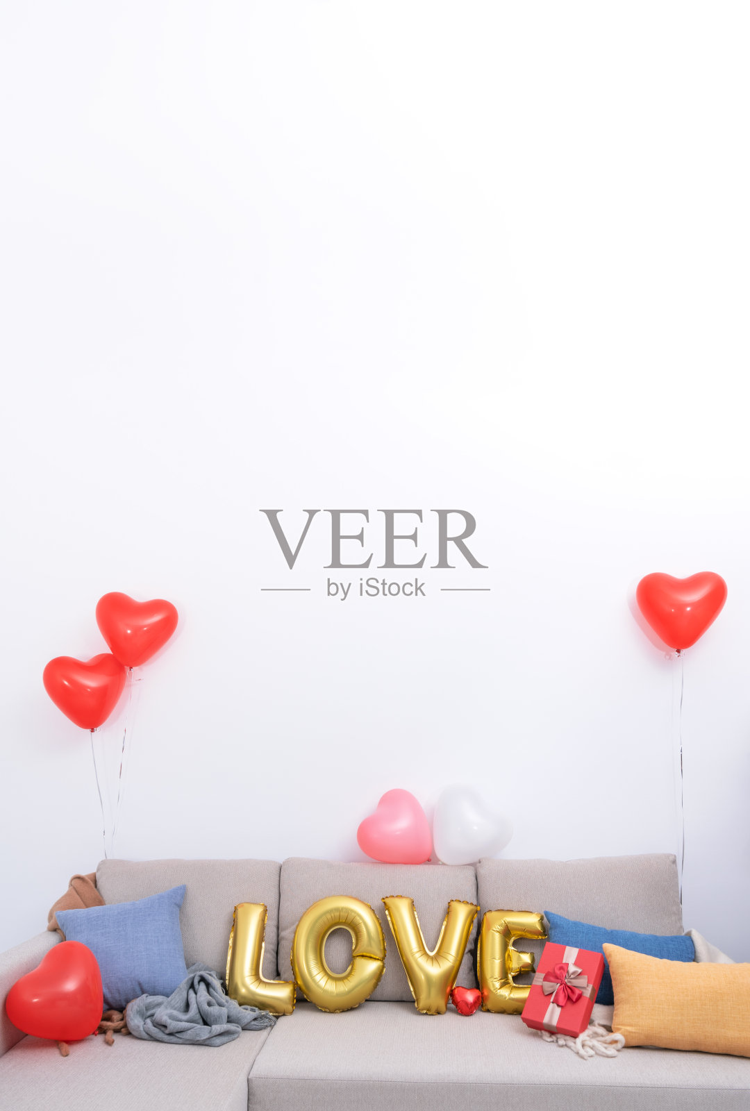 把爱情气球和礼物放在沙发上，以白色墙壁为背景，为情人节、母亲节准备惊喜。照片摄影图片