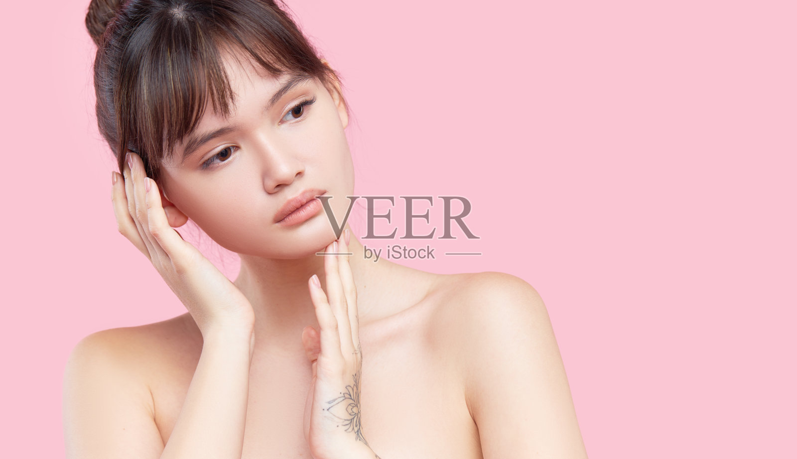 美丽的年轻亚洲韩国女人与清洁新鲜的皮肤触摸她自己的脸。面对治疗。美容、美容和水疗。粉红色的背景照片摄影图片
