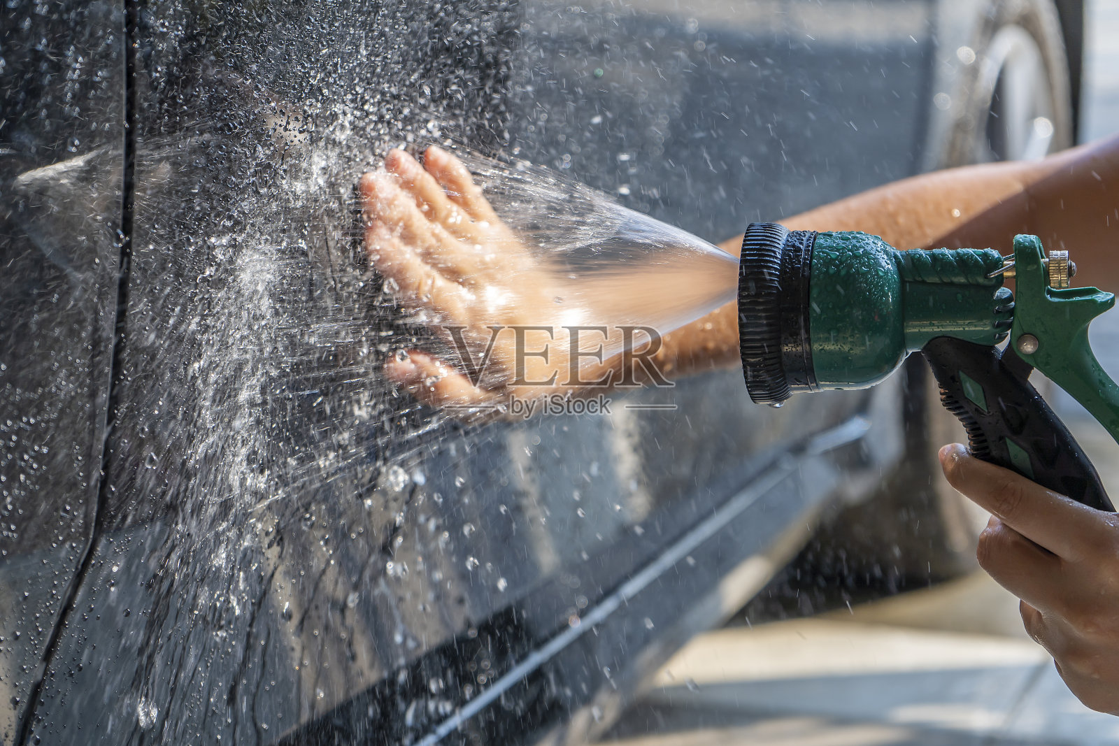 女人用手在洗车，她用双手擦去车上的灰尘和灰尘，防止车被划伤。照片摄影图片