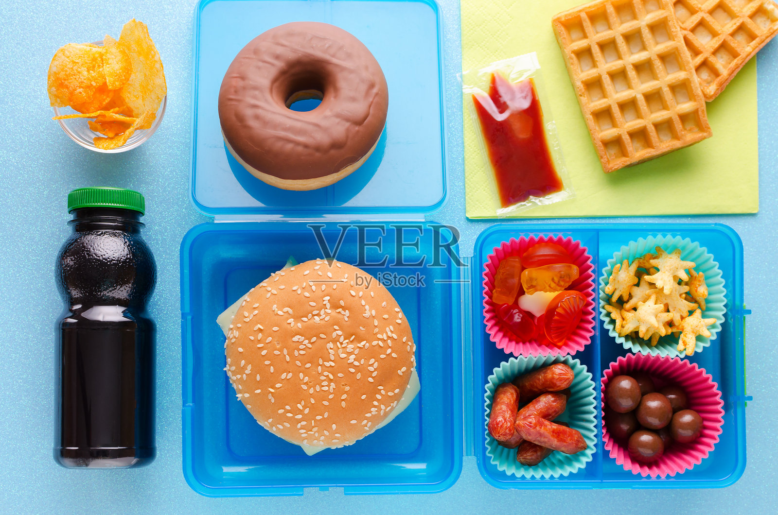 蓝色背景的不健康食物午餐盒，俯视图照片摄影图片