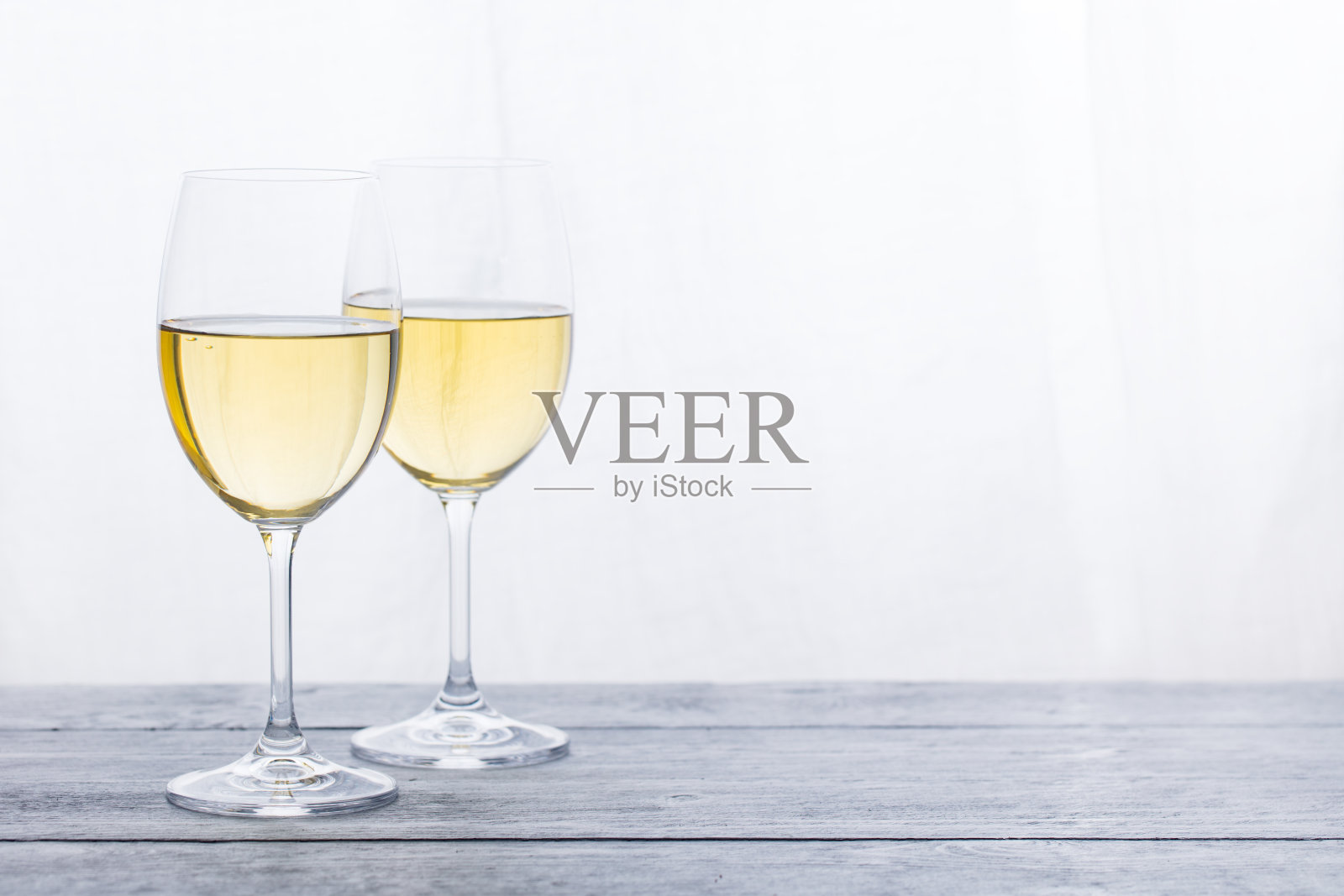 两杯白葡萄酒在灰色的木质背景上。副本的空间。照片摄影图片