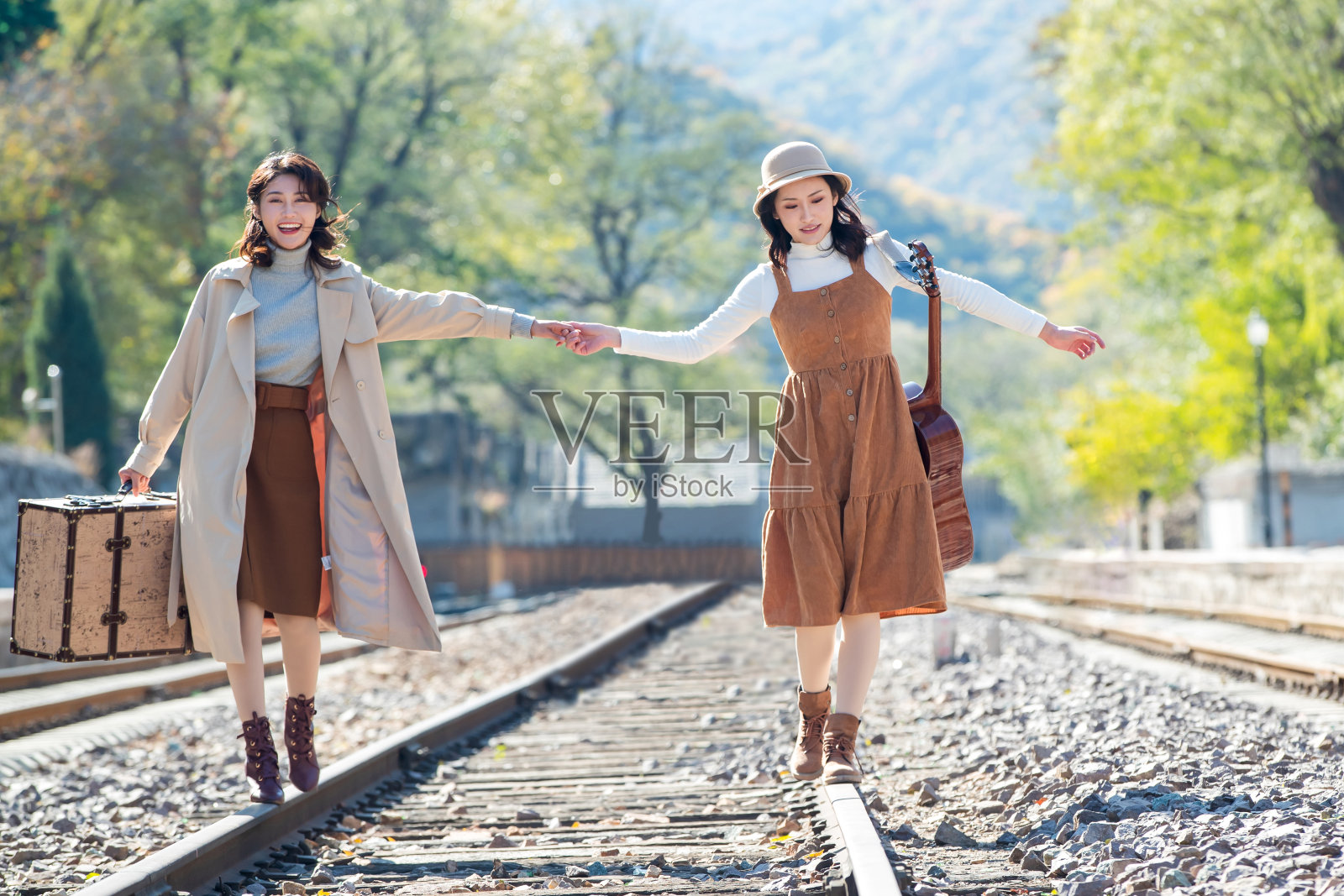 青年闺蜜手牵手走在铁轨上照片摄影图片