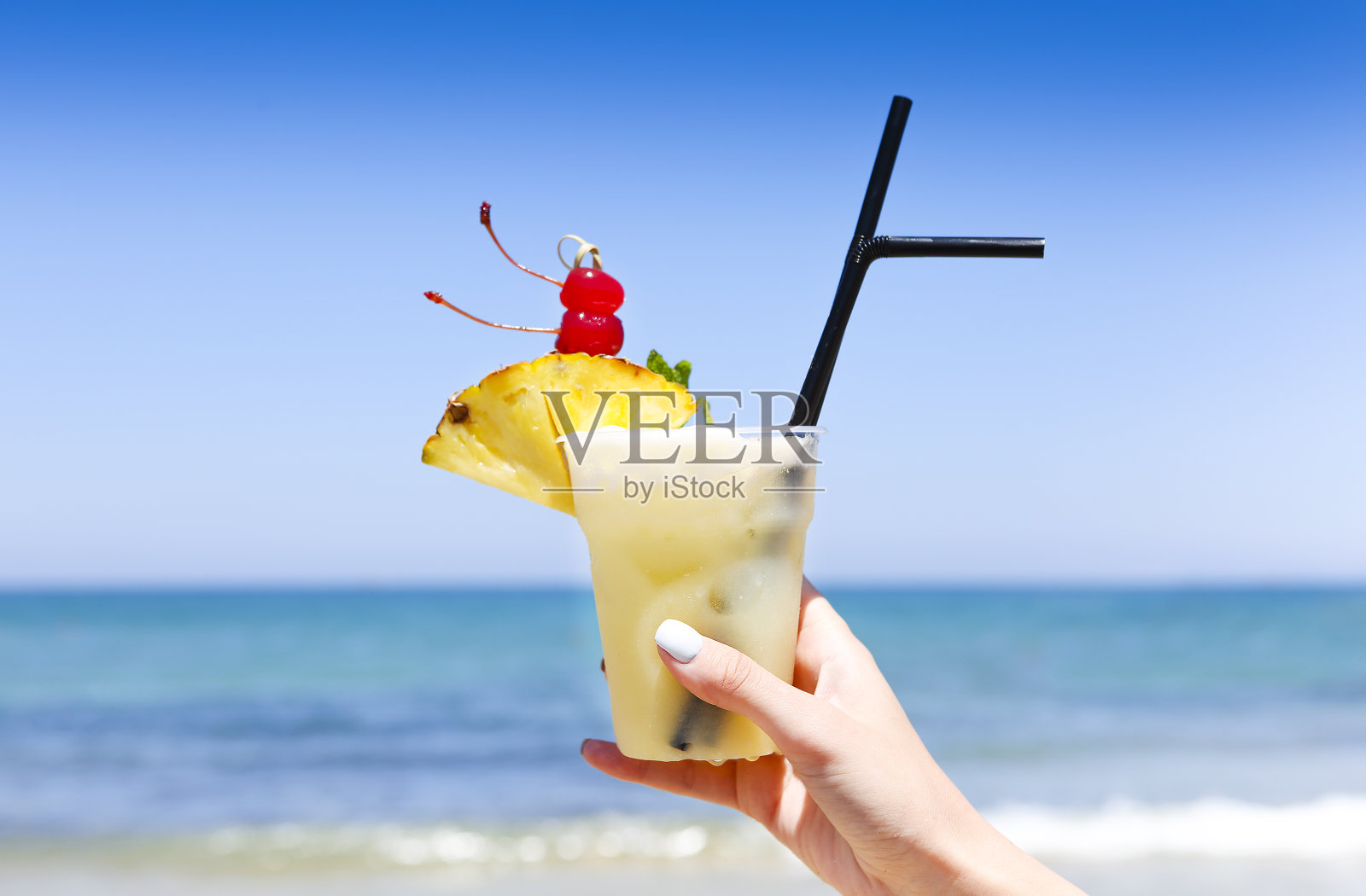 热带菠萝朗姆酒与菠萝在一个女人的手在一个热带海滩照片摄影图片