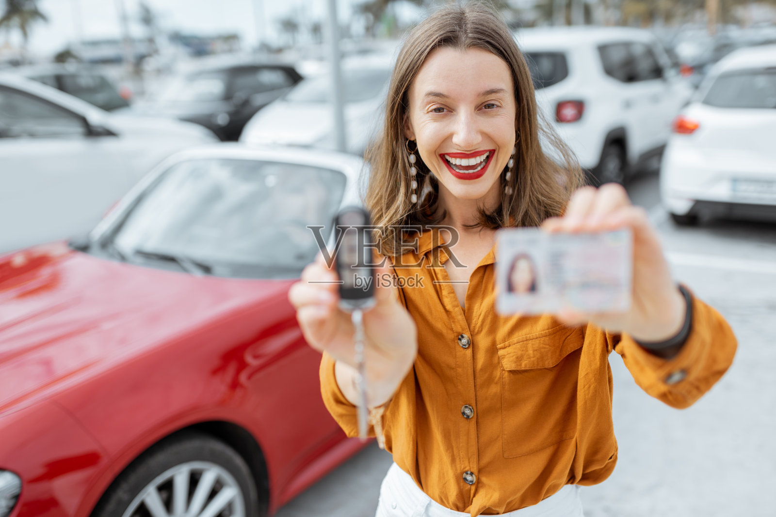 一个拿着钥匙和驾照的女人停在车旁边照片摄影图片