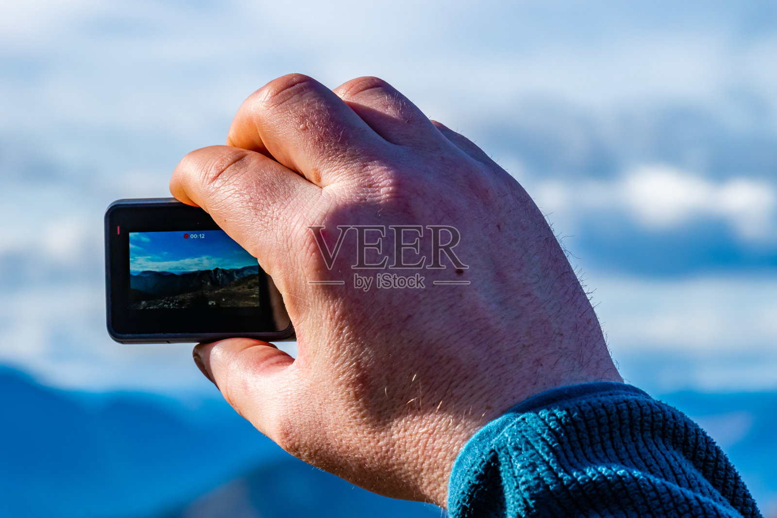 在一次徒步旅行中，一名男子拿着相机拍摄山上的景色照片摄影图片