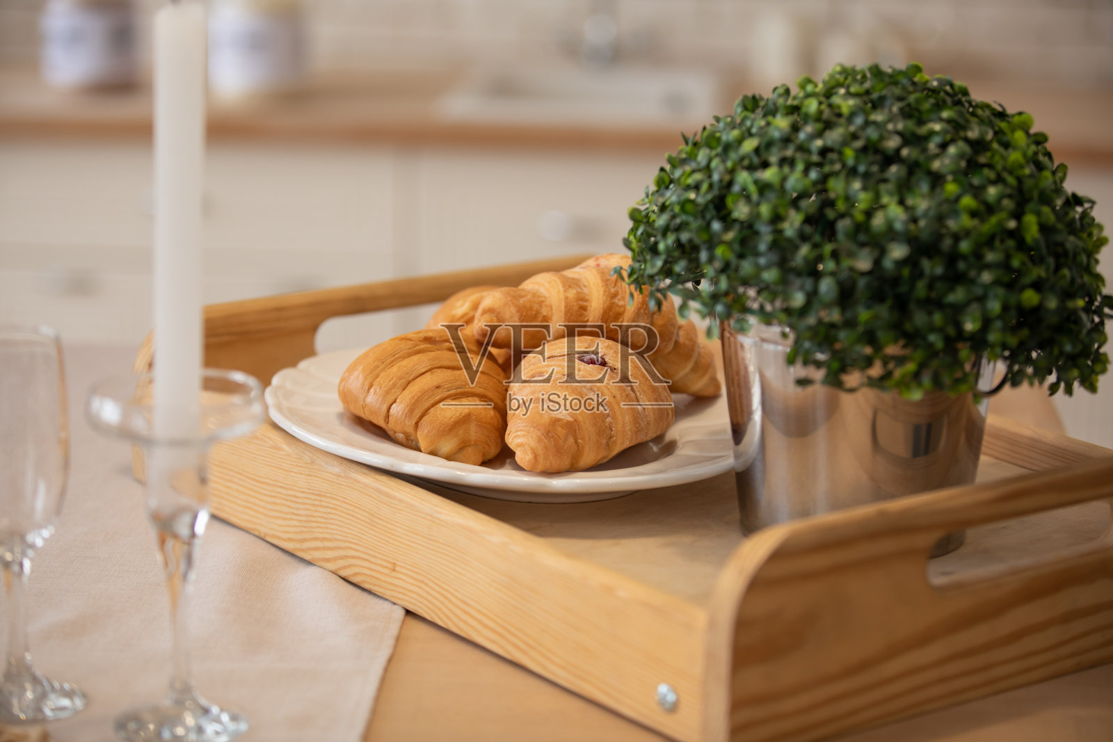 厨房的木桌上放着盛着牛角面包的盘子和插着花的花瓶。健康清淡的早餐。照片摄影图片