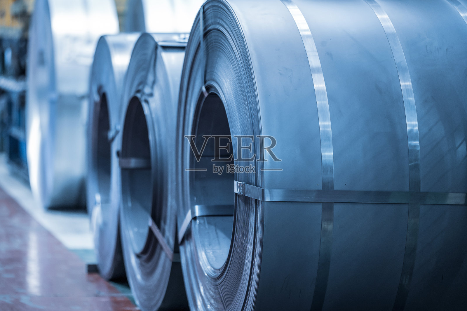 工业背景。大型钢卷存放在工业仓库内，蓝色色调的形象。照片摄影图片