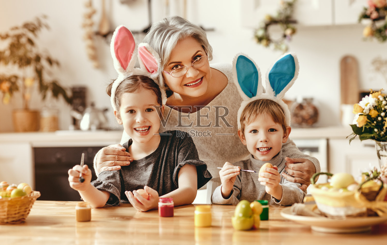复活节快乐!家人的祖母和孩子们为节日画鸡蛋照片摄影图片