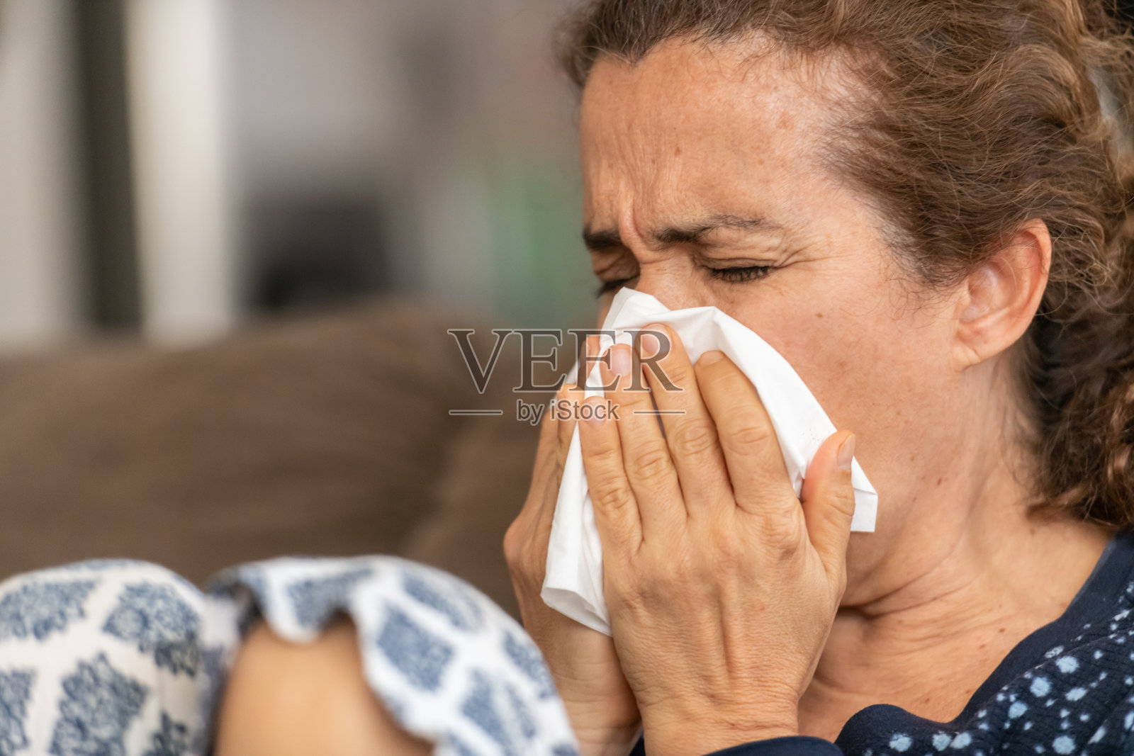 一个成熟的女人得了流感，用纸巾打喷嚏照片摄影图片