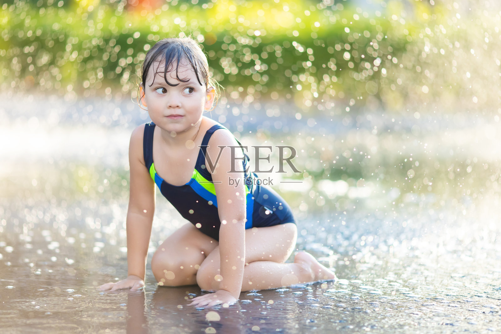 小女孩在公园的水上游乐场玩水玩得很开心。夏天的一天照片摄影图片