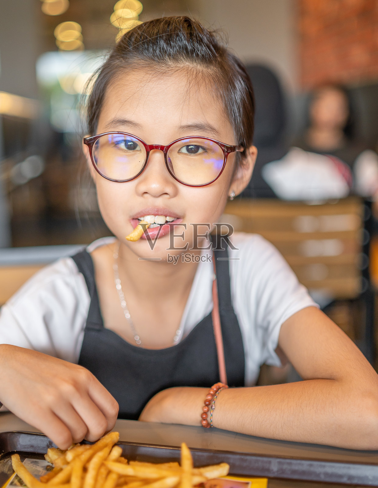 一个年轻女孩吃薯条的中号照片照片摄影图片